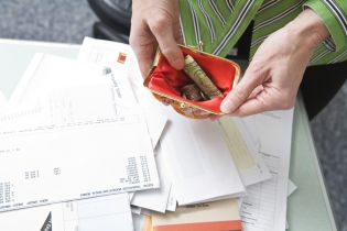 portfel - kobieta trzyma otwarty portfel w tle dokumenty finansowe